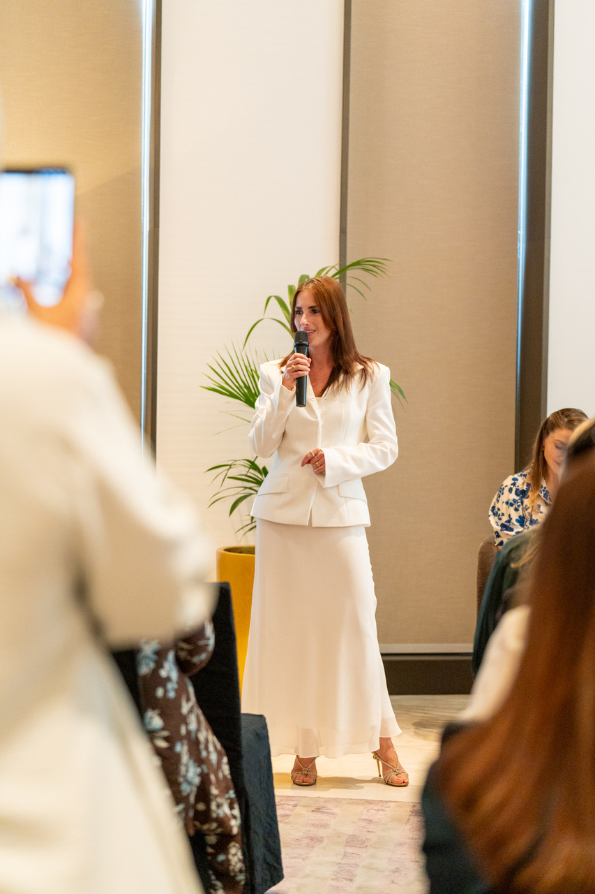 Renata Gabay speaking, holding a microphone.